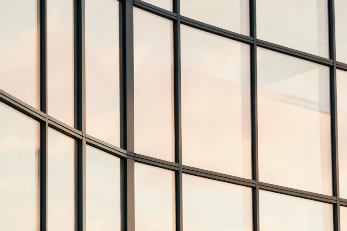 Glazen kantoorgevel die een zachte lucht weerspiegelt